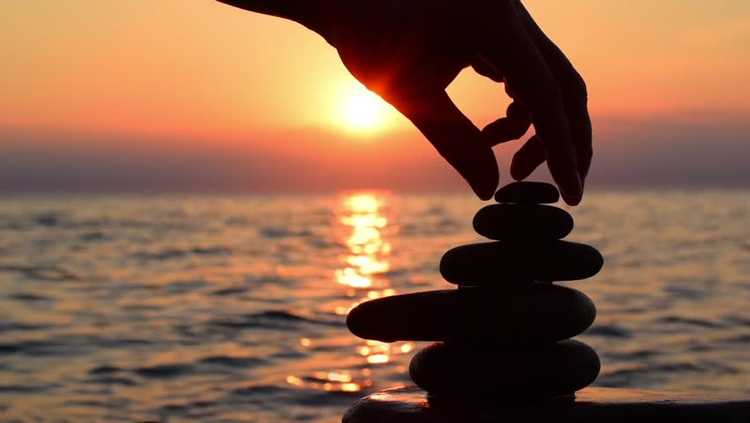 Balanced cone of stones on the seashore at sunrise